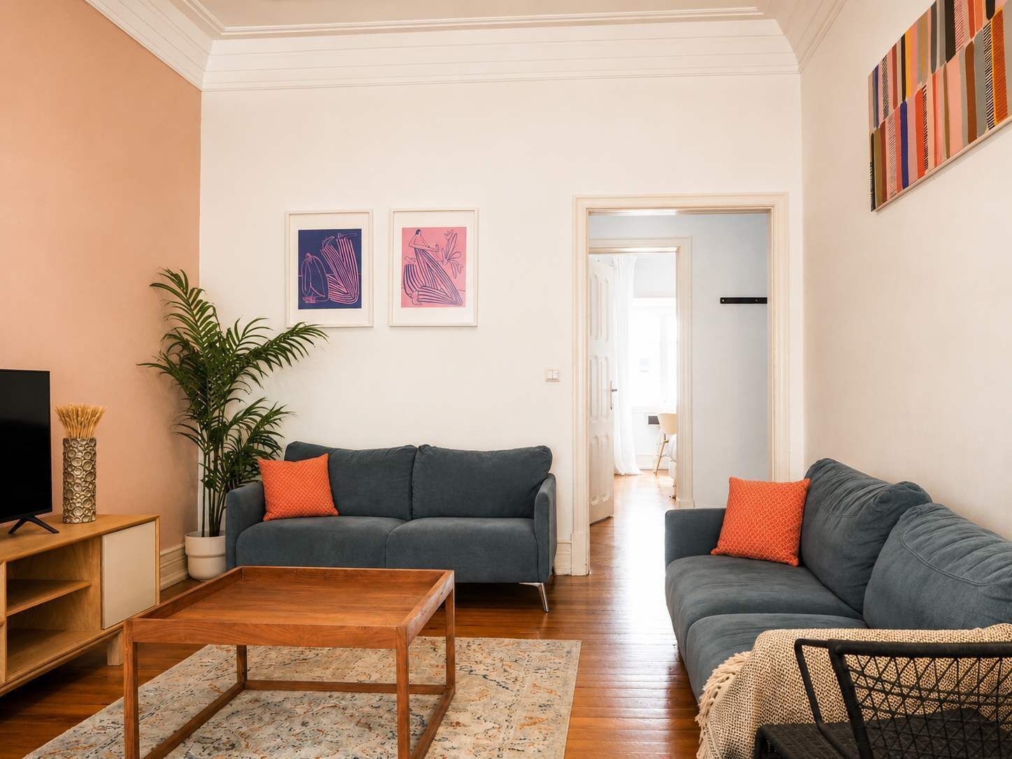 A living room with two sofas, a coffee table, a TV, and framed artwork on the wall.