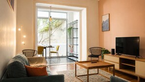 Una sala de estar con sofá, mesa de centro, televisor y estantería.