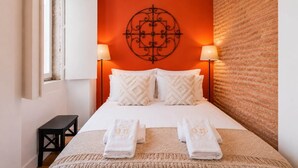 Ein Hotelzimmer mit einem Bett, zwei Nachttischlampen, einem Wanddekor und einem kleinen Tisch.