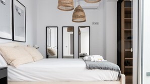 A modern bedroom with a bed, bedside tables, a wardrobe, and three mirrors. - Grand House in the Heart of Puerto - Modern, Renovated, Near Beach, 3 Terraces, WIFI (Puerto de Sagunto)