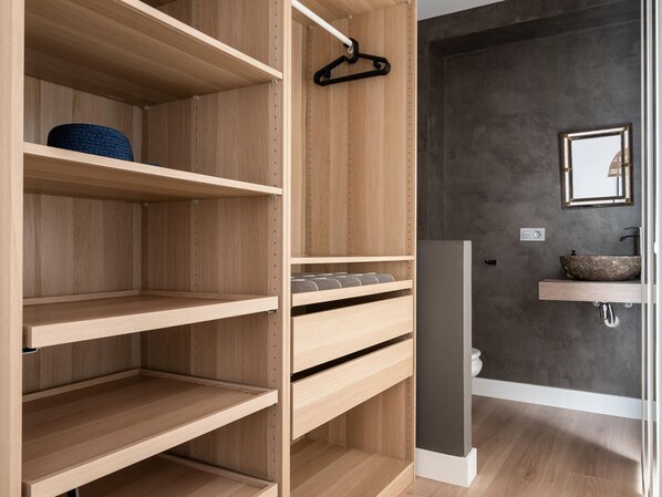 A modern bathroom with a wooden vanity, a large mirror, and a dark wall.