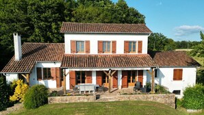 Una casa de dos pisos con techo de tejas, un porche cubierto y un pequeño jardín.