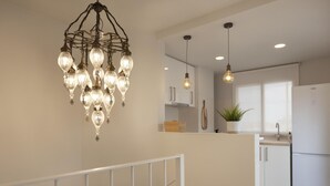 Una cocina moderna con armarios blancos, una isla central e iluminación colgante.