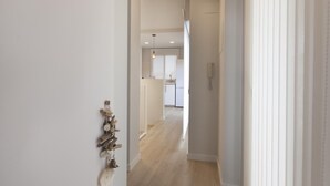 Un pasillo que conduce a una cocina con armarios blancos y piso de madera.