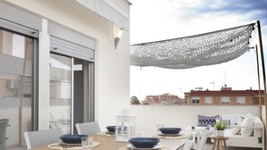 Un área de comedor exterior moderna con mesa de madera, sillas blancas y cuencos azules.