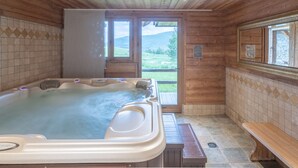 Una cabaña de madera con un jacuzzi, un banco y vistas al exterior.