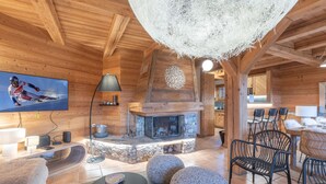 Interior acogedor de una cabaña de madera con chimenea de piedra, un televisor y muebles modernos.
