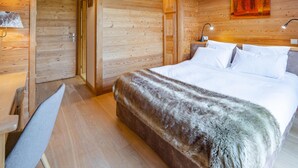 Un dormitorio de cabaña de madera con una cama, lámparas de noche, un armario de madera y un cuadro en la pared.