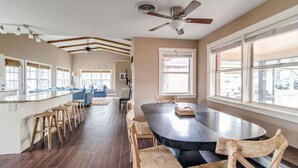 Une cuisine spacieuse dotée d’un grand îlot central, de tabourets de bar en bois et d’une table à manger avec des chaises.
