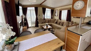 A compact living space with a sofa set, a dining table, and a kitchen area. - Captivating 3-bed Caravan at Golden Palm Skegness (Skegness)
