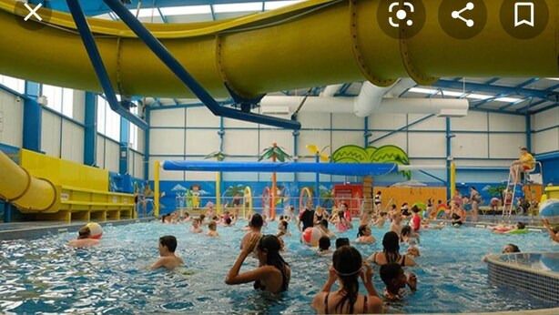 An indoor swimming pool with multiple lanes, a water slide, and various water play structures. - Captivating 3-bed Caravan at Golden Palm Skegness (Skegness)