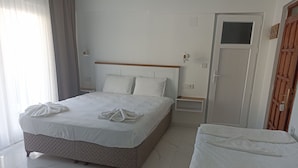 A hotel room with a large bed, a bedside table, a nightstand, a wardrobe, and a door.