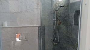 A modern bathroom with a glass-enclosed shower, a toilet, and a sink.