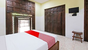 A room with a bed, a wooden bench, a television, and large wooden doors. - Hotel O Kopi Klotok Homestay Syariah (Secang)