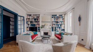 Un salon avec deux canapés, une cheminée et des étagères remplies de livres.