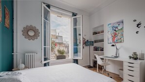 Une chambre dotée d’un grand lit, d’un bureau et donnant sur le balcon extérieur.