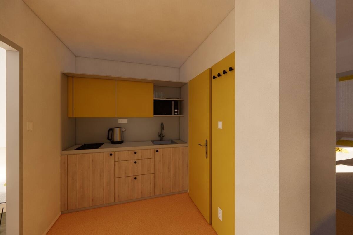 A compact kitchen with wooden cabinets, a microwave, and a kettle.