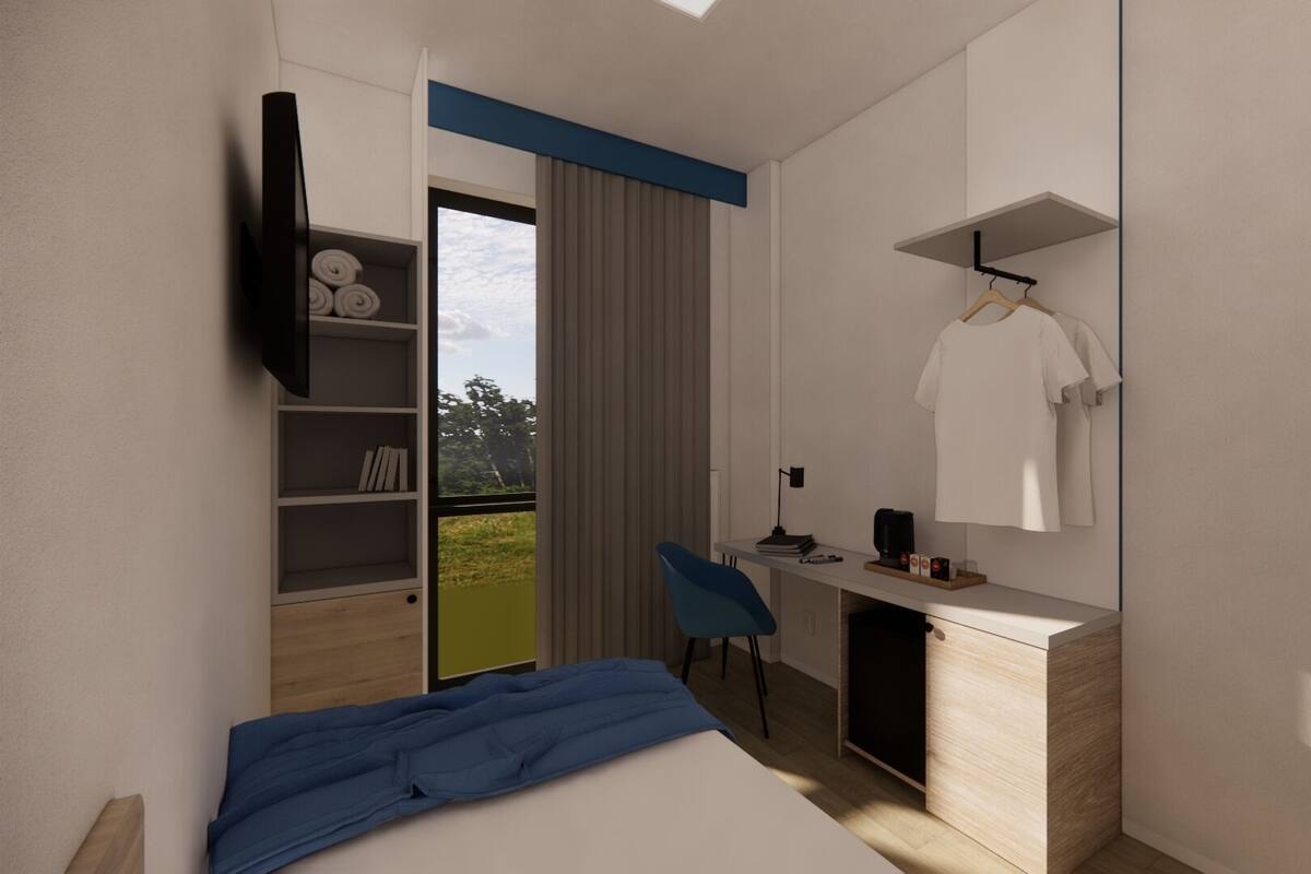 A modern bedroom with a bed, a desk, a chair, a wardrobe, and a large window with a view of greenery.