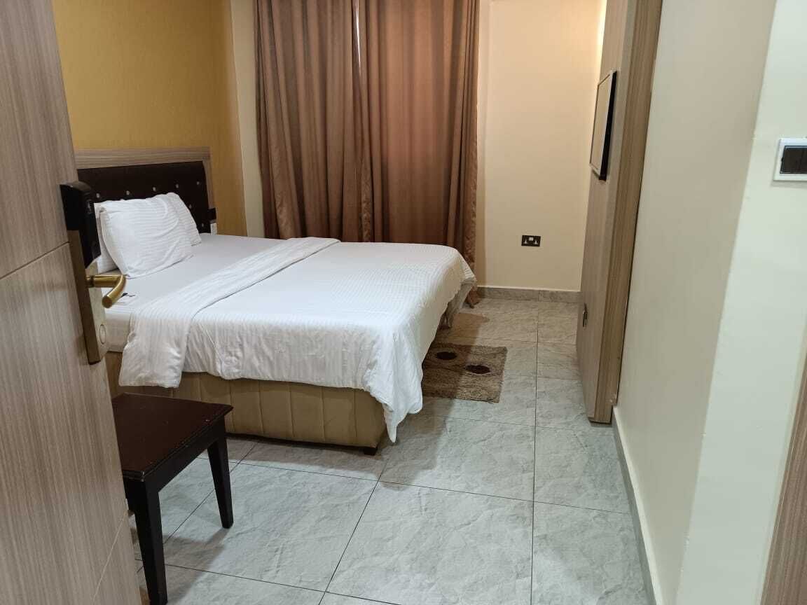 A hotel room with a bed, a small table, and a curtain.