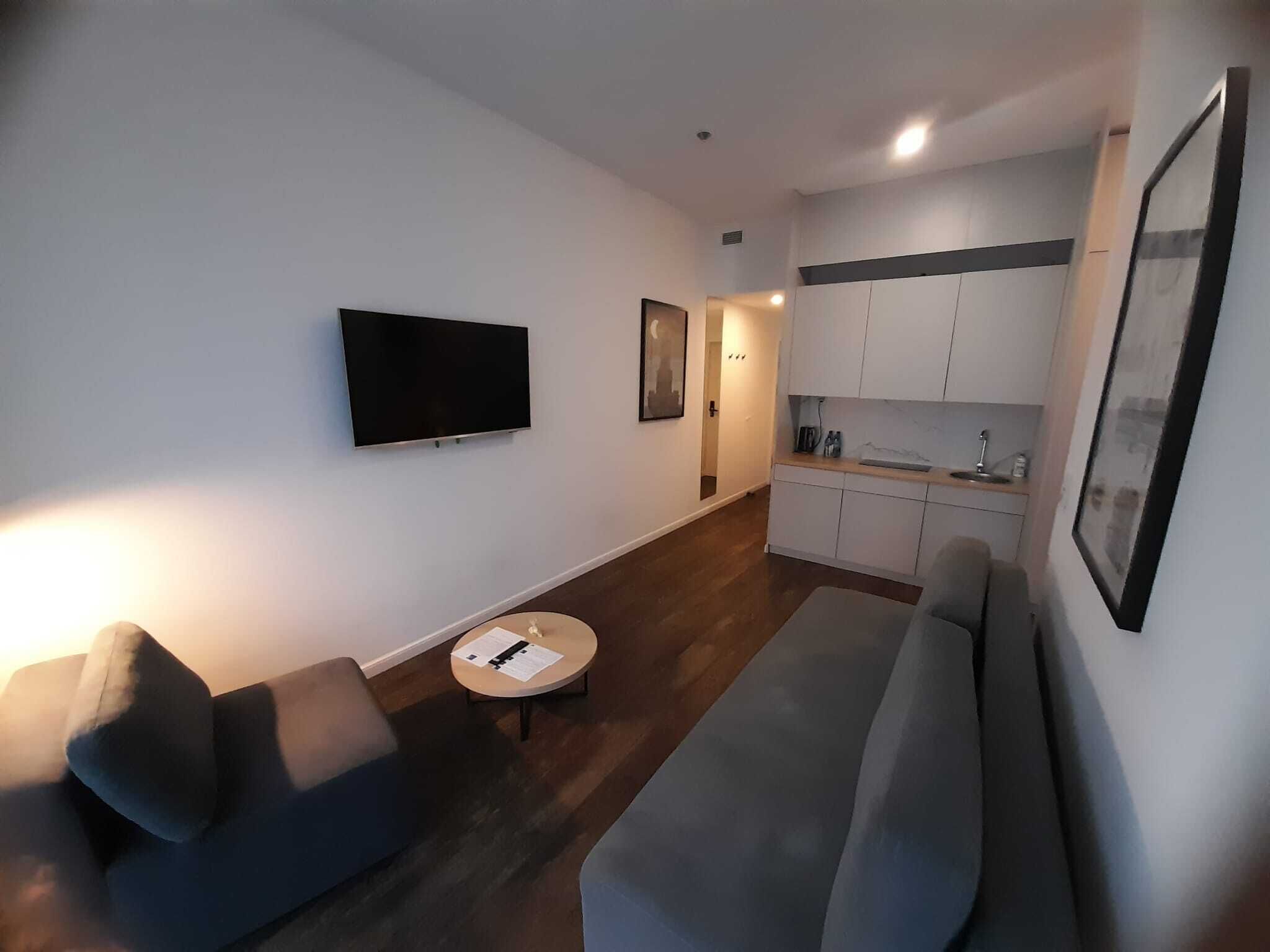 Uma sala de estar moderna com um sofá, uma mesa de centro e uma TV de tela plana fixada na parede.