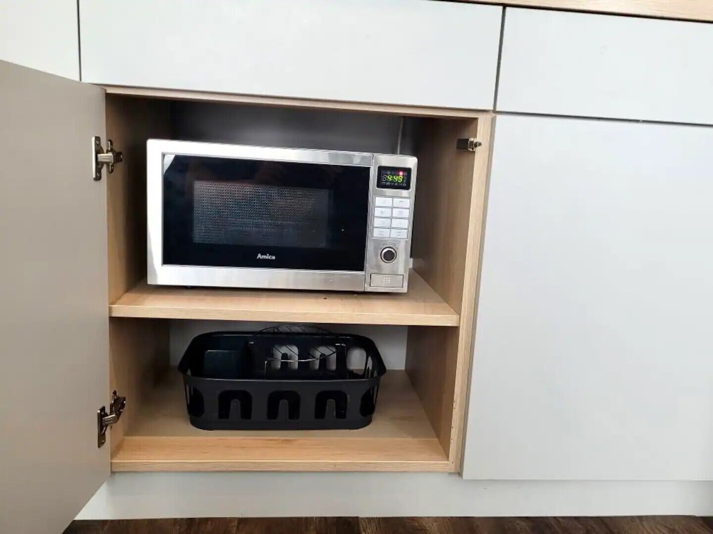 Eine Mikrowelle steht auf einem Regal in einem Küchenschrank.