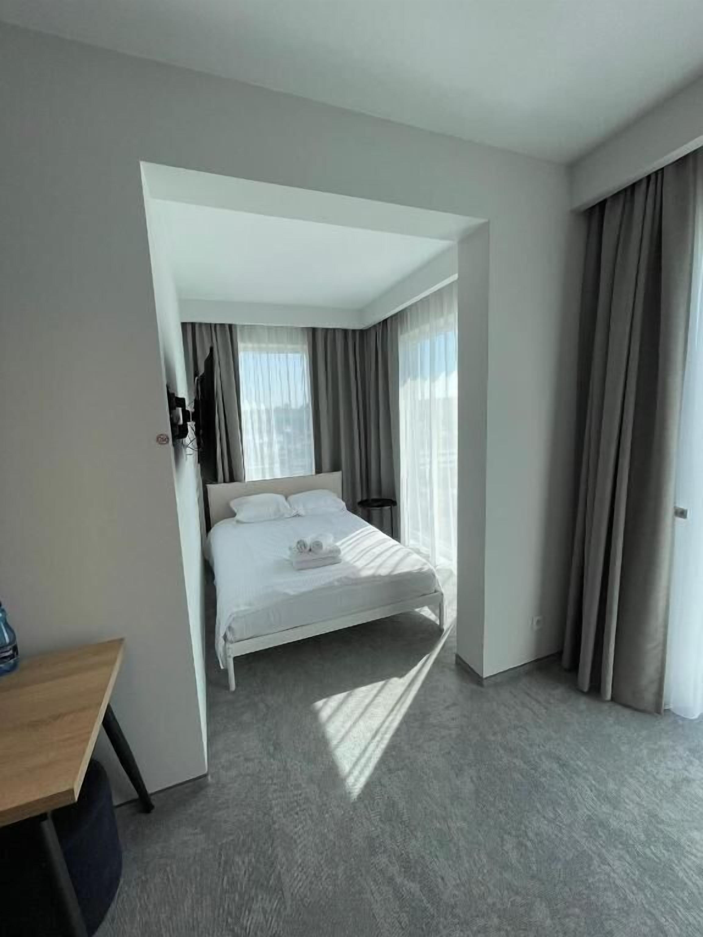 A modern hotel room with a neatly made bed, a desk, and a chair.