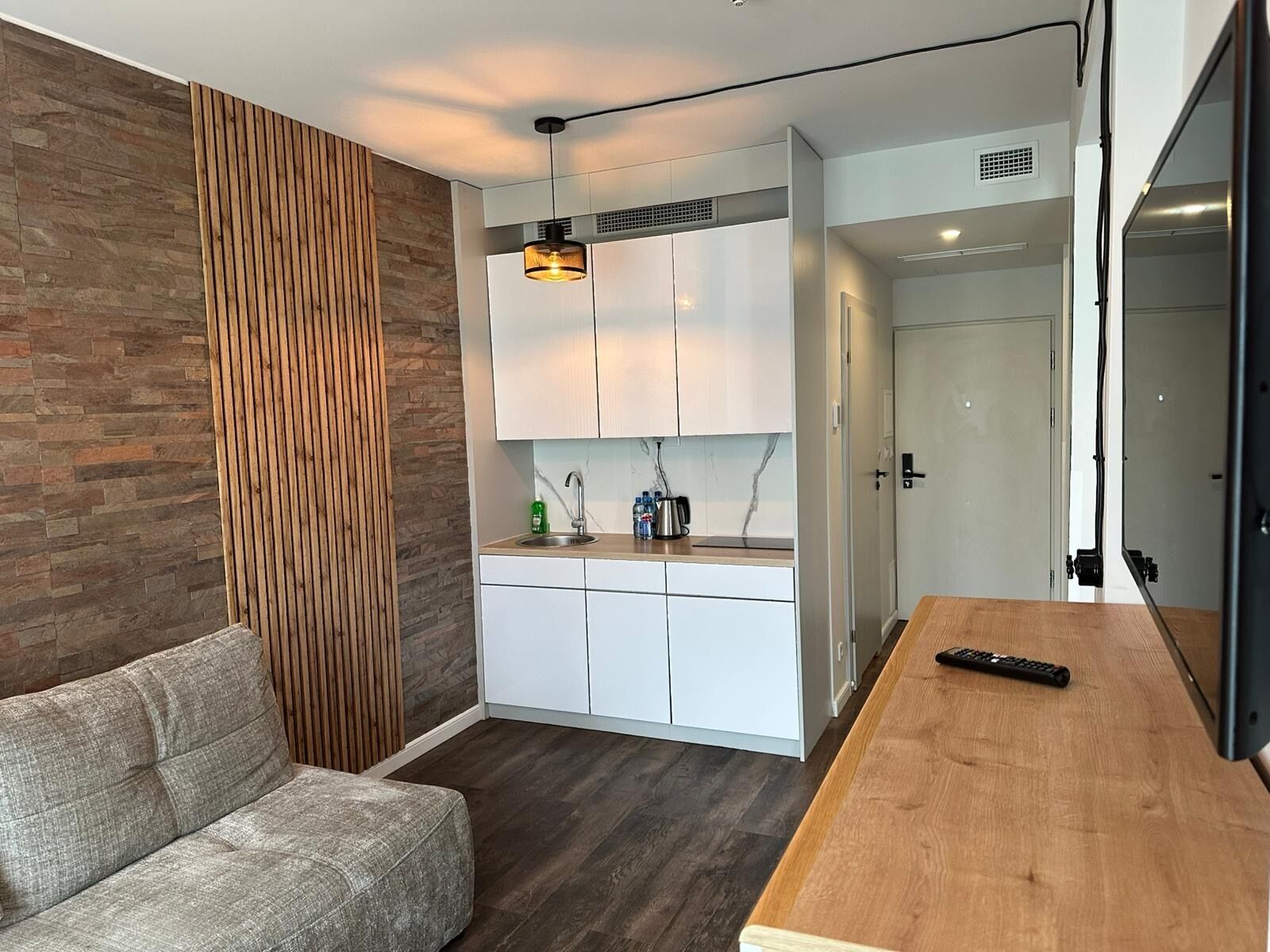 A modern kitchen with white cabinets, a wooden countertop, and a hanging light fixture.
