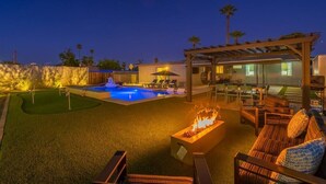 A well-lit outdoor area with a pool, fire pit, and seating area. - BackyardOasis - FamilyRetreat Villa - HeatedPool (Phoenix)