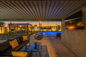 Eine Außenpatio-Terrasse mit Pool, Sitzgelegenheiten und einer Pergola.