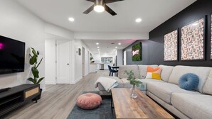 A modern living room with a sofa, coffee table, and a flat-screen TV. - The No Bad Days Villa - Family Retreat -Central (Phoenix)