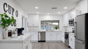 A modern kitchen with white cabinetry, stainless steel appliances, and a large window providing natural light. - The No Bad Days Villa - Family Retreat -Central (Phoenix)