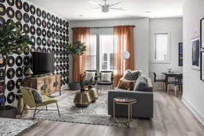 A living room with a wall of vinyl records, a sofa, a coffee table, and a television.