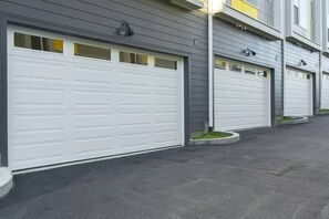 A row of residential garages with grey siding and white garage doors.