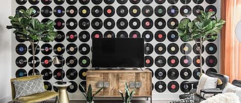 A living room with a wall of vinyl records, a wooden cabinet, and a television.