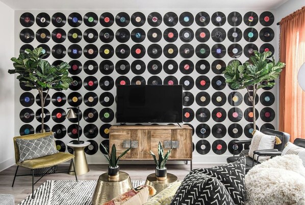 A living room with a wall of vinyl records, a wooden cabinet, and a television.