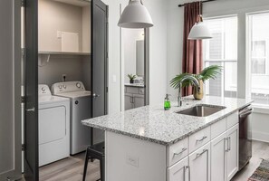 A modern kitchen with a granite countertop, built-in appliances, and a large window with curtains.