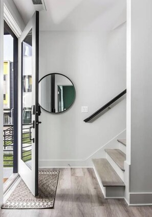 A modern interior with a staircase, a round mirror, and a patterned rug.