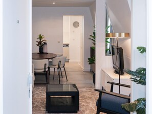 Een moderne woonkamer met een eethoek, een flatscreen televisie en een salontafel.