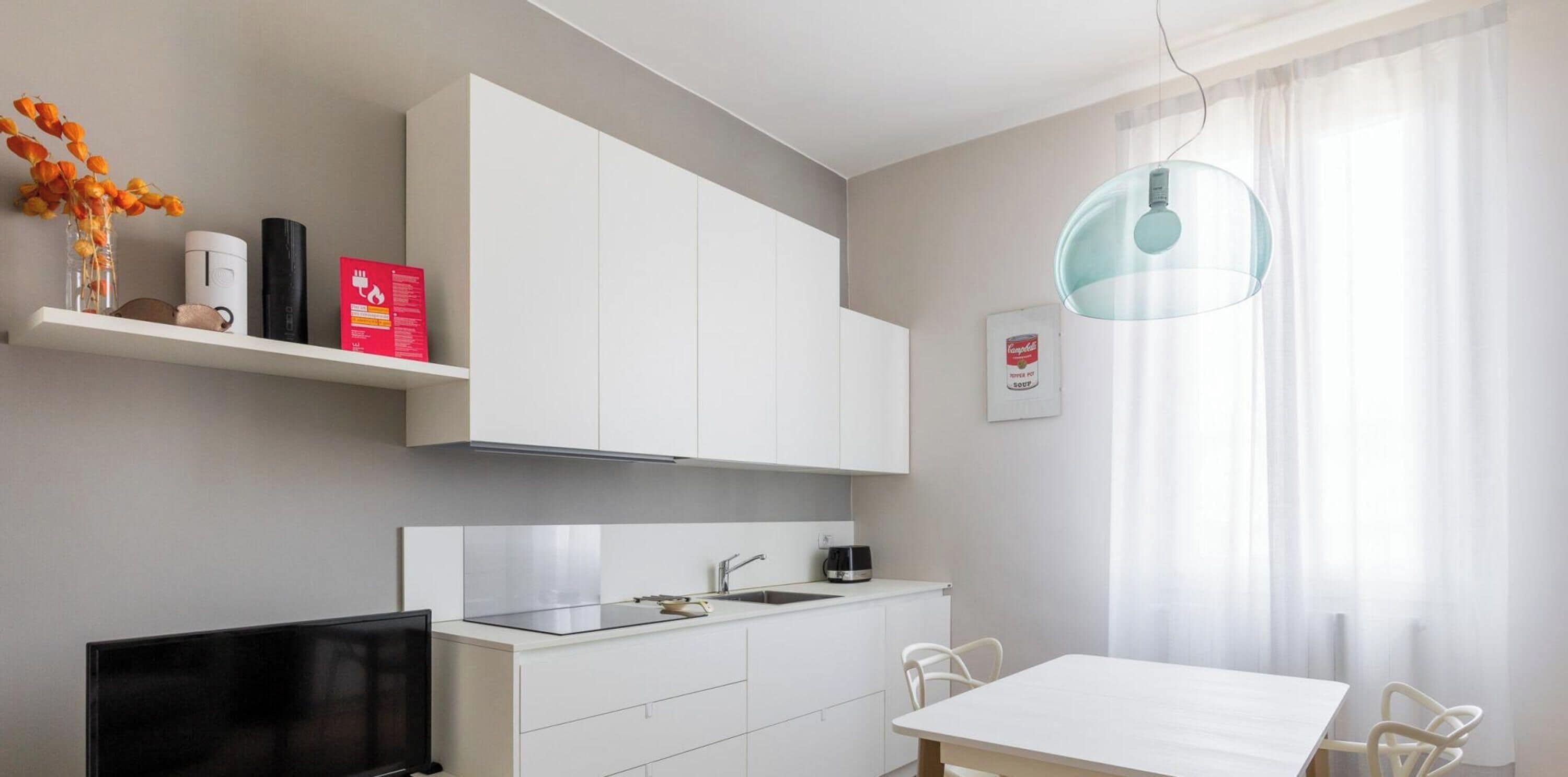 Una cocina moderna con armarios blancos, estufa integrada y una zona de comedor con mesa y sillas.