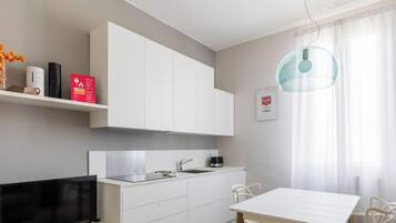 Una cocina moderna con armarios blancos, estufa integrada y una zona de comedor con mesa y sillas.