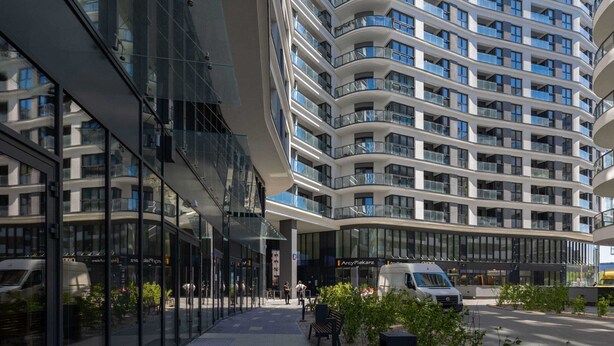 A modern multi-story building with balconies, large windows, and a glass facade.