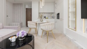 A modern living room with a sofa, a coffee table with a vase of flowers, and a dining area with a round table and chairs.