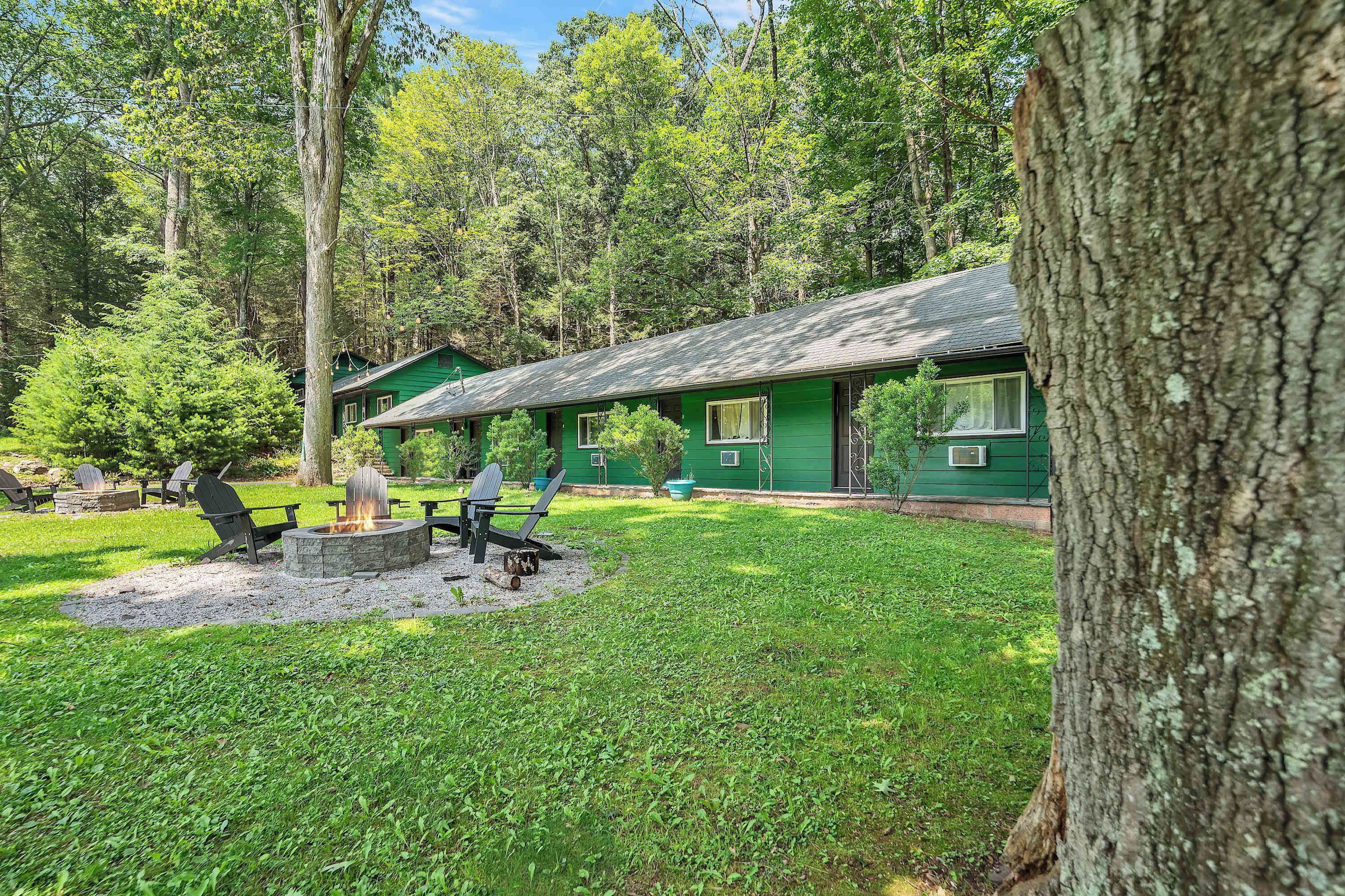A green lodge with a fire pit and outdoor seating.