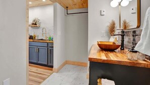 A modern kitchen with wooden cabinets, a wooden countertop, and a sink.
