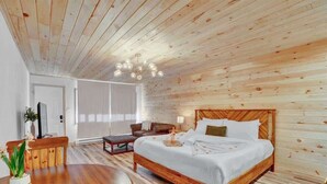A wooden-paneled room with a bed, a dining table, and a TV.