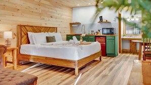 A wooden cabin-style bedroom with a bed, bedside table, and a small desk with a chair.
