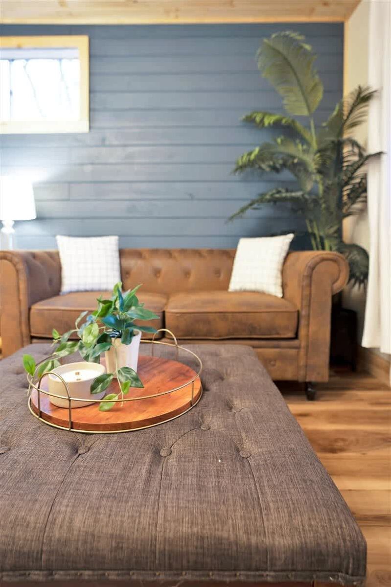 Una mesa de centro de madera con una bandeja metálica, una planta en maceta y una vela.