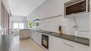 Una cocina moderna con armarios blancos, encimera de granito, horno integrado y microondas.