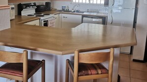 Una cocina con isla de madera, armarios blancos, estufa, lavaplatos y refrigerador.