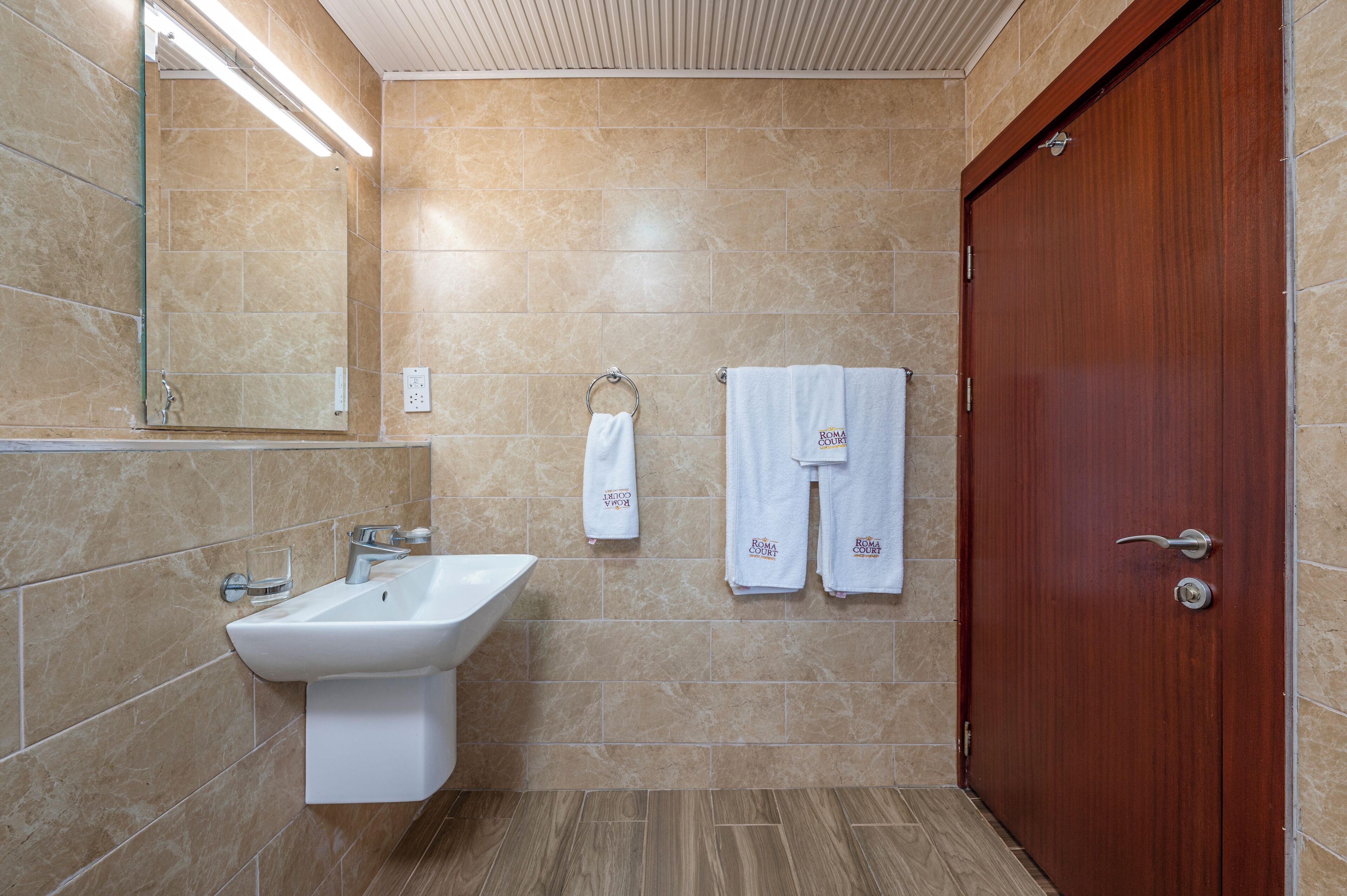 A bathroom with a sink, mirror, towel rack, and a wooden door.